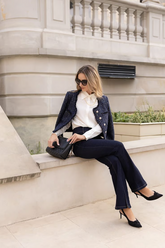 a lady in a shirt, a black tweed coat, and a pair of jeans